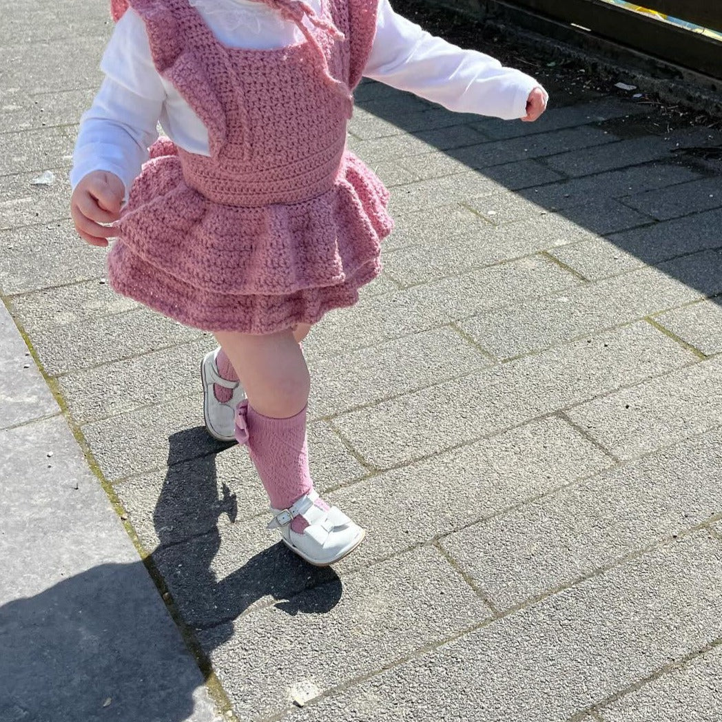 Little Girls crocheted Romper Suit with twin layered frilly skirt and frills around the straps, pictured in colour pale rose